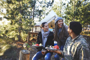 Glückliche Freunde lachen und essen auf einem Campingplatz im Wald - CAIF23664