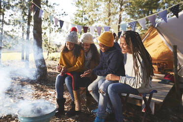 Glückliches lesbisches Paar und Kinder entspannen sich auf einem Campingplatz im Wald - CAIF23669