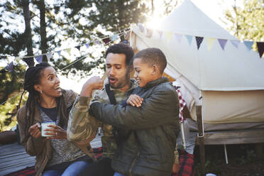 Verspielter Vater, der für seinen Sohn auf dem Campingplatz Bizepsmuskeln trainiert - CAIF23672