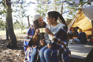 Glückliches lesbisches Paar, das sich auf einem sonnigen Campingplatz entspannt und Kaffee trinkt - CAIF23688
