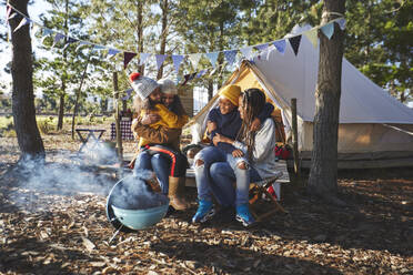 Glückliches, liebevolles lesbisches Paar mit Kindern auf einem sonnigen Campingplatz - CAIF23690