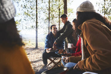 Glückliche Familie beim Essen auf dem sonnigen Campingplatz - CAIF23706