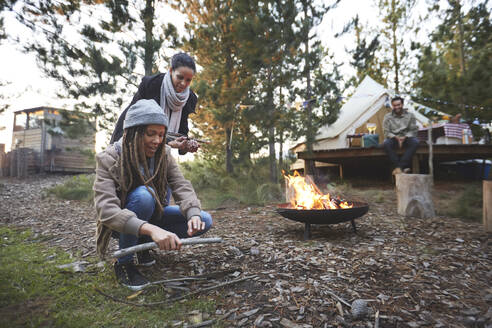 Freunde beim Sammeln von Brennholz auf einem Campingplatz im Wald - CAIF23708