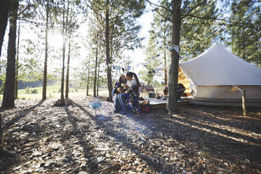 Glückliches, liebevolles lesbisches Paar entspannt sich, trinkt Kaffee auf einem sonnigen Campingplatz im Wald - CAIF23711