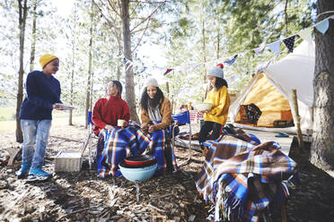 Lesbisches Paar und Kinder beim Grillen auf dem Campingplatz im sonnigen Wald - CAIF23723