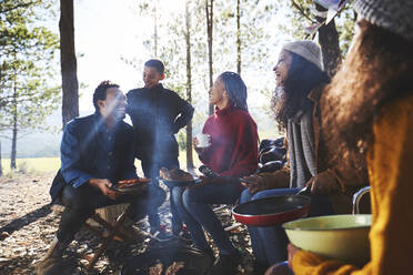 Familie und Freunde beim Essen auf einem sonnigen Campingplatz im Wald - CAIF23726