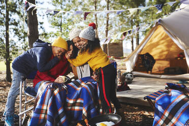 Happy, affectionate lesbian couple and kids hugging at campsite - CAIF23732