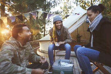 Freunde spielen Karten auf dem Campingplatz - CAIF23740