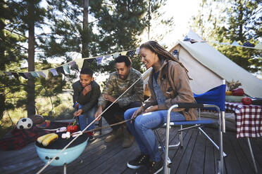 Familie kocht Gemüse am Grill auf dem Campingplatz - CAIF23741