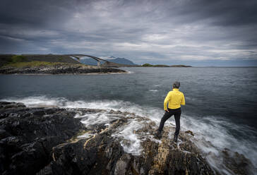 Hiker admiring the Atlantic Road from cliffs washed by waves, More og Romsdal county, Norway, Scandinavia, Europe - RHPLF13049