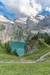 Blick von oben auf zwei Wanderer auf einem Weg oberhalb des Oeschinensees, Berner Oberland, Kandersteg, Kanton Bern, Schweiz, Europa - RHPLF13055