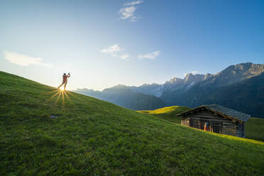 Mann im Sonnenlicht beim Fotografieren von Piz Badile und Cengalo, Tombal, Soglio, Val Bregaglia, Kanton Graubünden, Schweiz, Europa - RHPLF13063