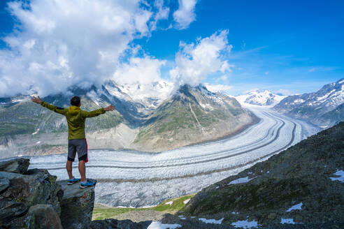 Mann jubelnd mit ausgestreckten Armen mit Blick auf den Aletschgletscher vom Aussichtspunkt Eggishorn, Berner Alpen, Kanton Wallis, Schweiz, Europa - RHPLF13072