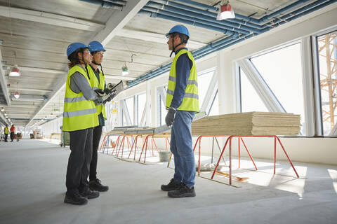 Weibliche und männliche Ingenieure diskutieren in voller Länge auf der Baustelle, lizenzfreies Stockfoto