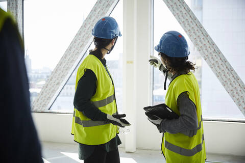 Seitenansicht von Ingenieurinnen, die auf einer Baustelle diskutieren, lizenzfreies Stockfoto