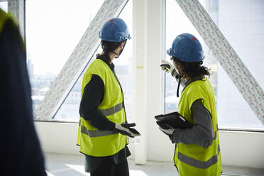 Side view of female engineers discussing at construction site - MASF15250