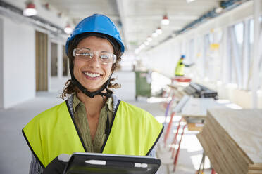 Porträt einer lächelnden Vorarbeiterin mit digitalem Tablet auf einer Baustelle - MASF15252