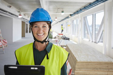 Porträt einer lächelnden Ingenieurin in reflektierender Kleidung auf einer Baustelle - MASF15256
