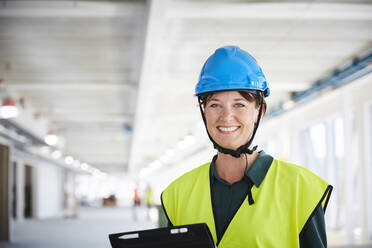 Porträt eines lächelnden weiblichen Bauleiters in reflektierender Kleidung auf der Baustelle - MASF15259