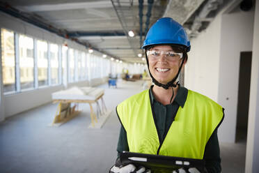 Porträt einer lächelnden Ingenieurin in Arbeitsschutzkleidung auf einer Baustelle - MASF15261