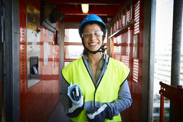 Porträt einer lächelnden Ingenieurin in reflektierender Kleidung auf einer Baustelle - MASF15262