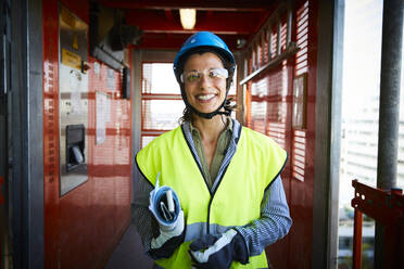 Portrait of smiling female engineer in reflective clothing at construction site - MASF15262