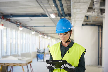 Selbstbewusste Ingenieurin in reflektierender Kleidung mit digitalem Tablet auf der Baustelle - MASF15263