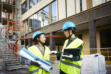 Weiblicher Ingenieur diskutiert mit einem Kollegen auf einer Baustelle - MASF15267
