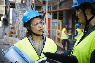 Ingenieurin diskutiert mit einem Kollegen auf der Baustelle - MASF15269