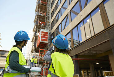 Ingenieurinnen in reflektierender Kleidung diskutieren auf einer Baustelle - MASF15272