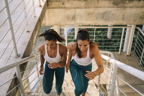 Zwei sportliche Zwillingsschwestern laufen eine Treppe hinauf - JCMF00324