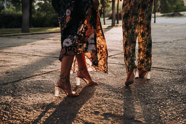 Feet of two elegant women walking outdoors at sunset - JCMF00329