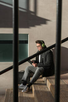 Young man is watching his tablet on the street - CAVF70480