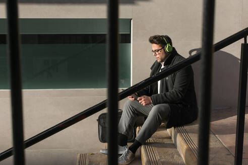 Young man is watching his tablet on the street - CAVF70481