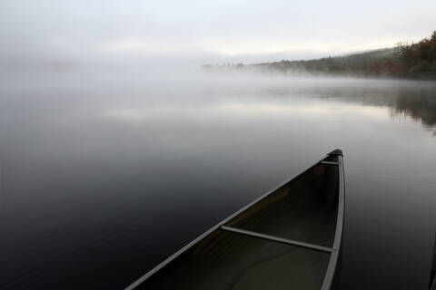 Ein schnittiges Kanu, das an einem Steg auf einem ruhigen Teich in Maine festgemacht ist., lizenzfreies Stockfoto