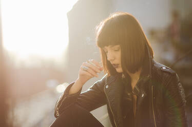 Portrait of a young woman with rock jacket smoking cigarette. - CAVF70509