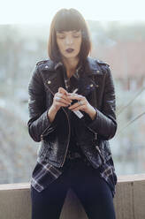 Portrait of a young woman with rock jacket smoking cigarette. - CAVF70511