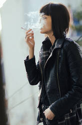Junges Mädchen beim Rauchen mit Rauchwolke im Gesicht - CAVF70512