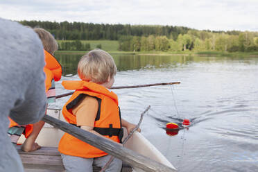 Erwachsener segelt mit Jungen auf einem Boot auf einem See, Finnland - CUF53725