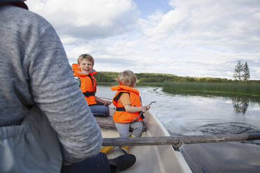 Erwachsener segelt mit Jungen auf einem Boot auf einem See, Finnland - CUF53726