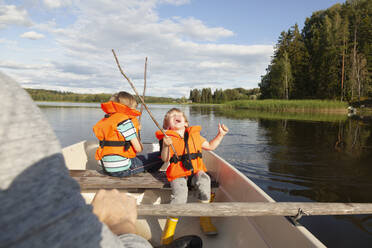 Adult sailing with excited boys on boat in lake, Finland - CUF53727