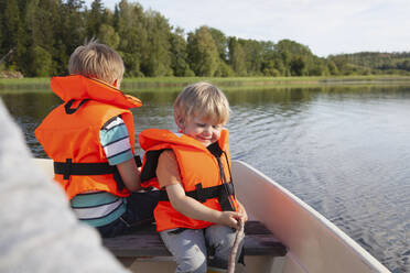 Erwachsener segelt mit Jungen auf einem Boot auf einem See, Finnland - CUF53728