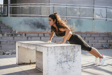 Young woman doing plank on concrete bench - CUF53759