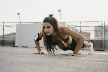 Young woman doing plank on rooftop deck - CUF53766