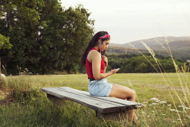 Young woman listening to music with earphones, hills in background, Wilhelminenberg, Vienna, Austria - CUF53824
