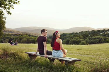Paar sitzt auf einer Bank mit Blick auf die Hügel, Wilhelminenberg, Wien, Österreich - CUF53825