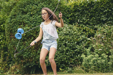 Mädchen spielt mit Diabolo im Garten - CUF53840