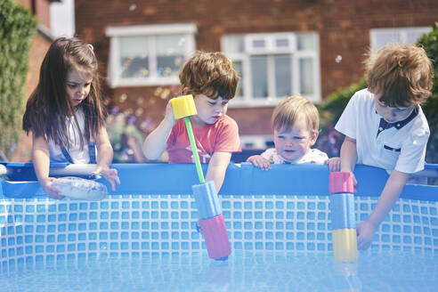 Kinder füllen die Wasserpistole am Pool - CUF53843