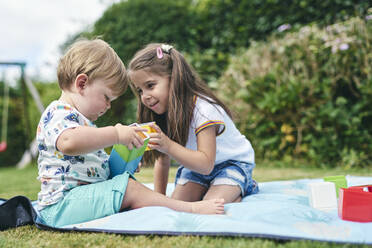 Schwestern spielen mit Blöcken auf einer Picknickdecke - CUF53846