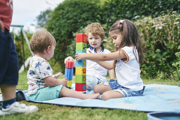 Bruder und Schwestern spielen mit Blöcken auf einer Picknickdecke - CUF53847